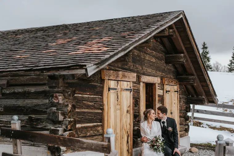 Alte Alphütte im Schnee, Brautpaar im Türrahmen